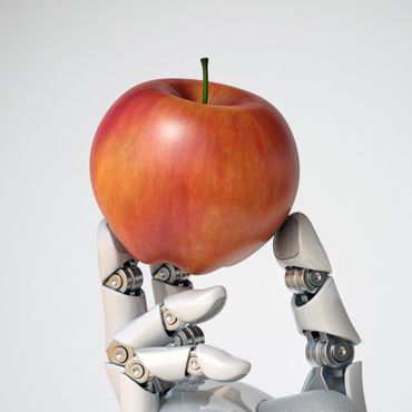 Ein Apfel wird von einem weißen Roboter in der Hand gehalten