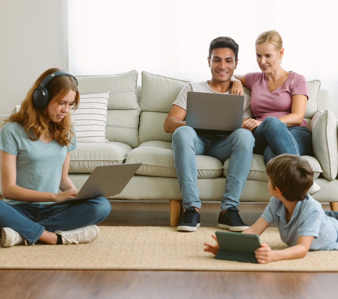 Frau und Mann sitzen auf Sofa, 2 Kinder auf dem Teppich surfen Internet