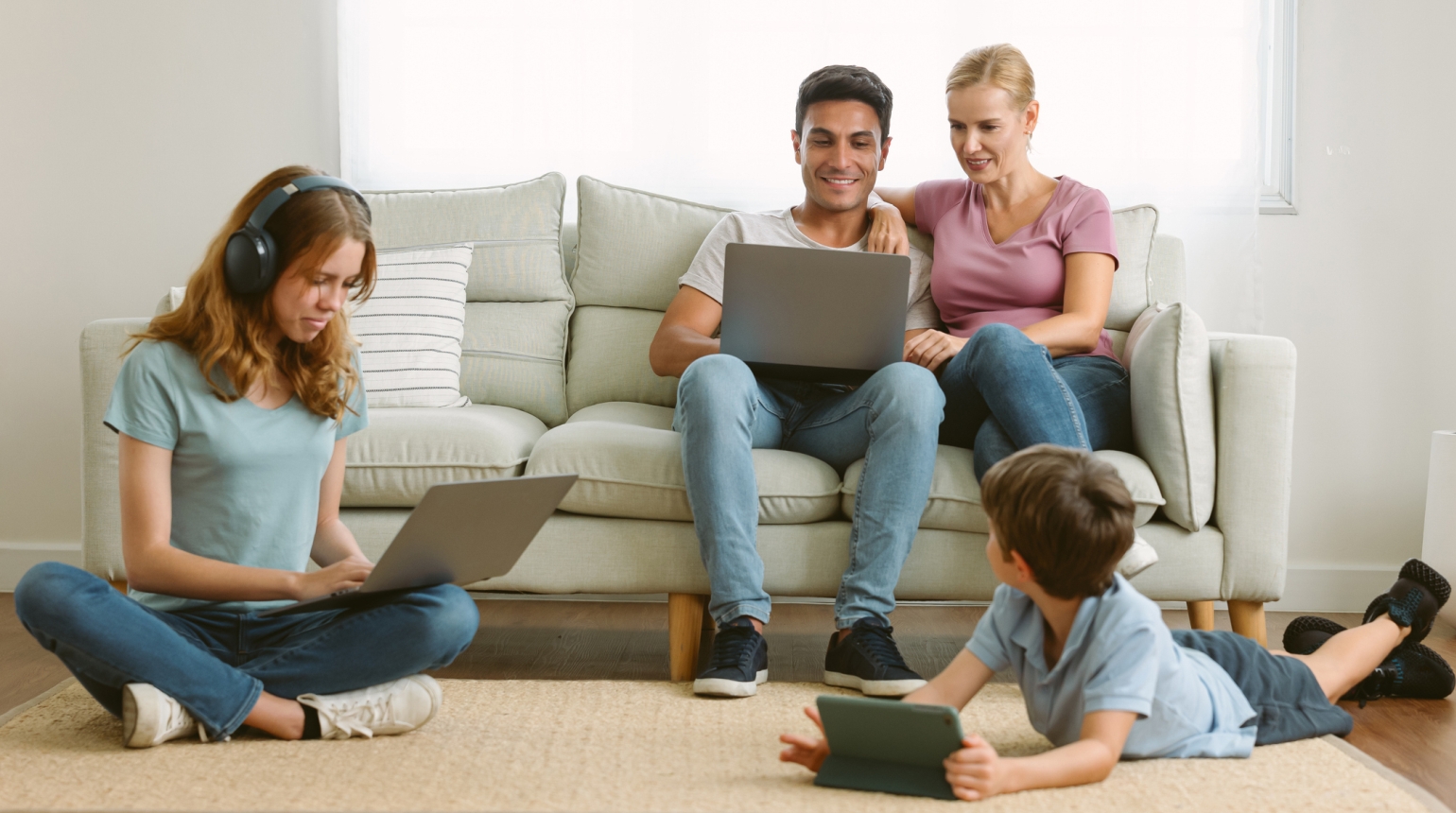 Frau und Mann sitzen auf Sofa, 2 Kinder auf dem Teppich surfen Internet